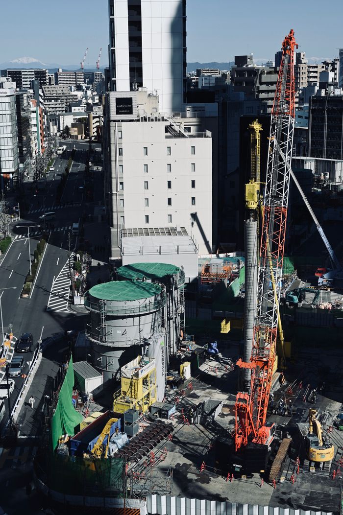 Aerial shot of an urban construction site in a bustling city center with cranes and buildings.