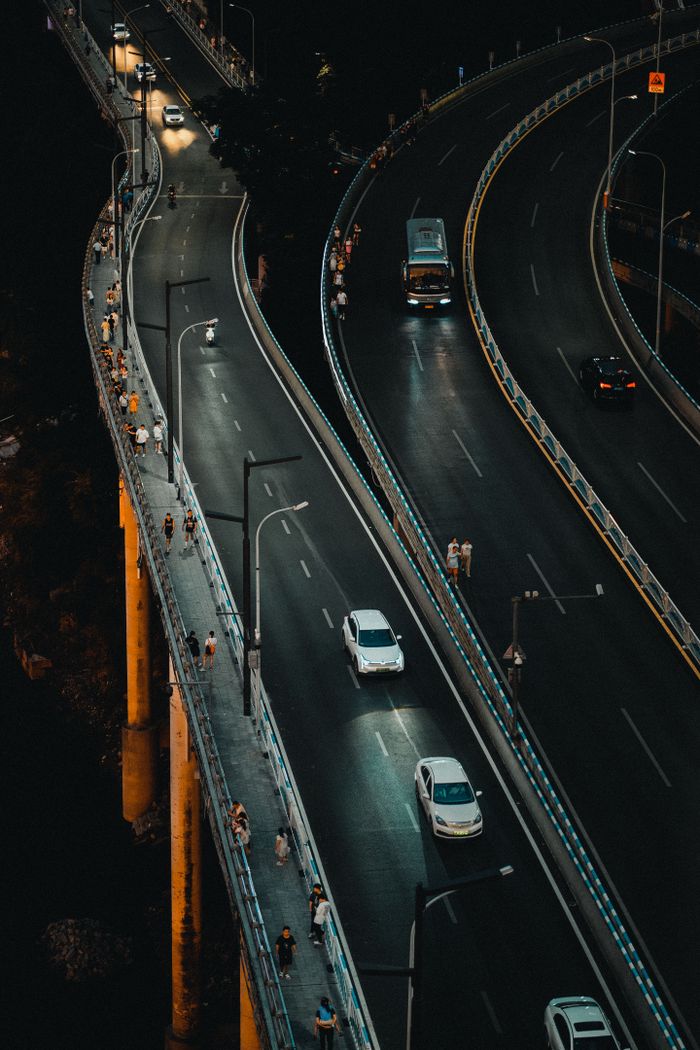 Aerial view of a lively urban highway with cars and pedestrians at night.